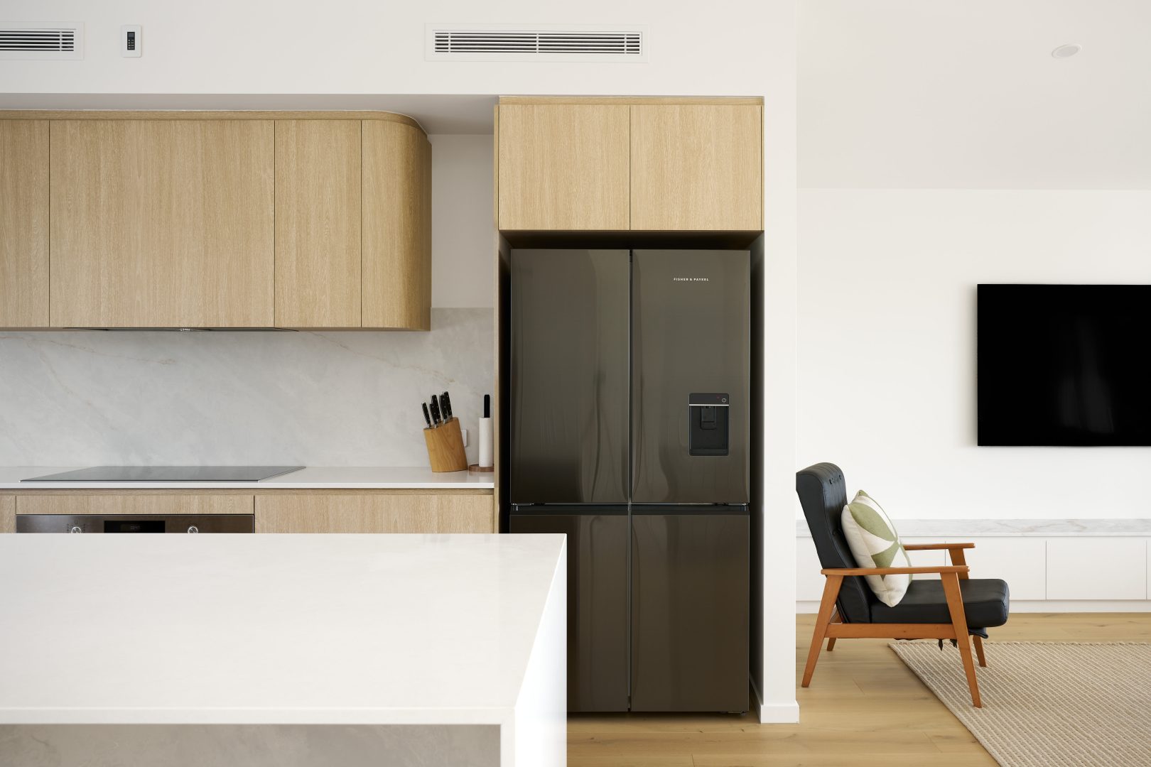 Modern kitchen with fridge and wooden cabinetry.