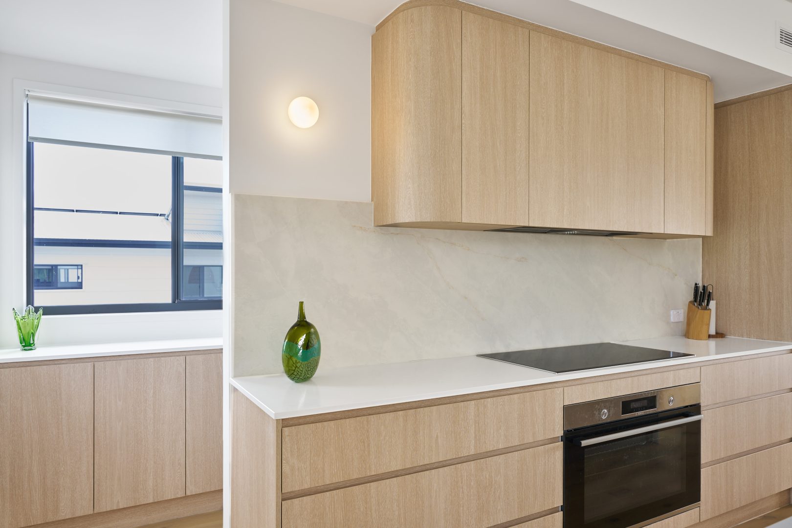 Modern kitchen with wooden cabinets and green vase.