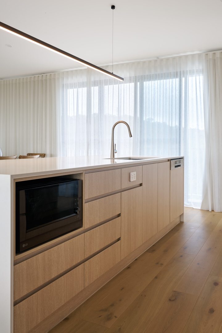 Modern kitchen with wooden island and built-in appliances.
