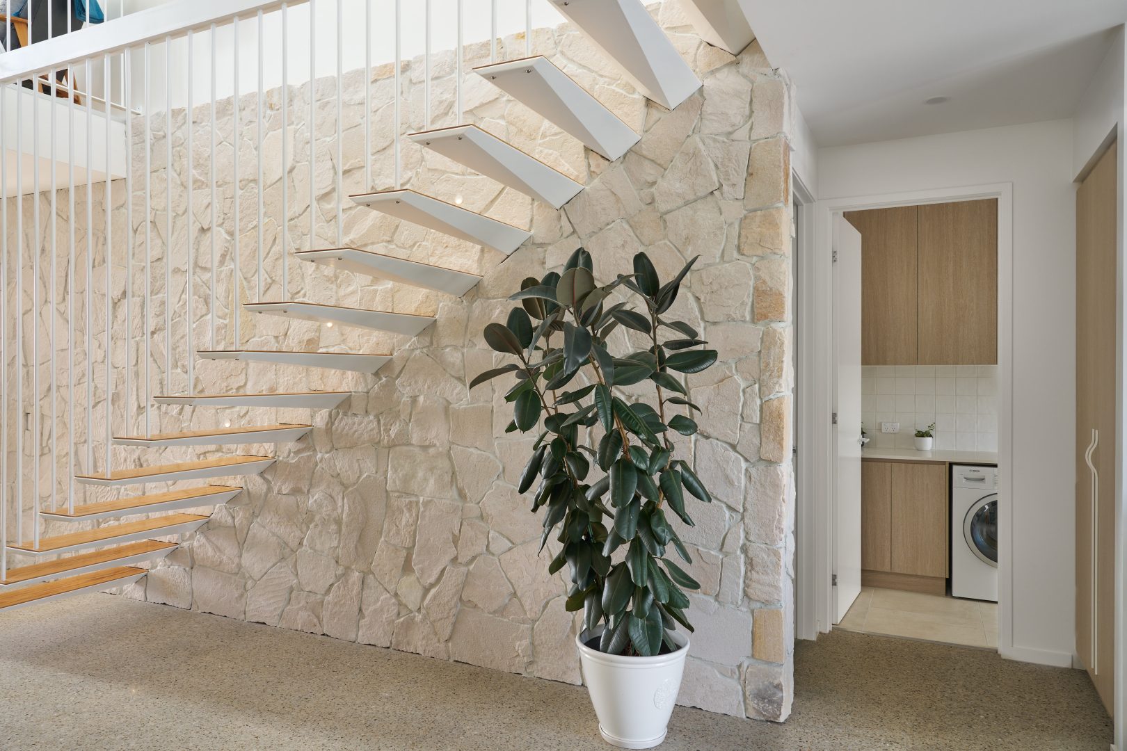 Modern staircase with plant and laundry room