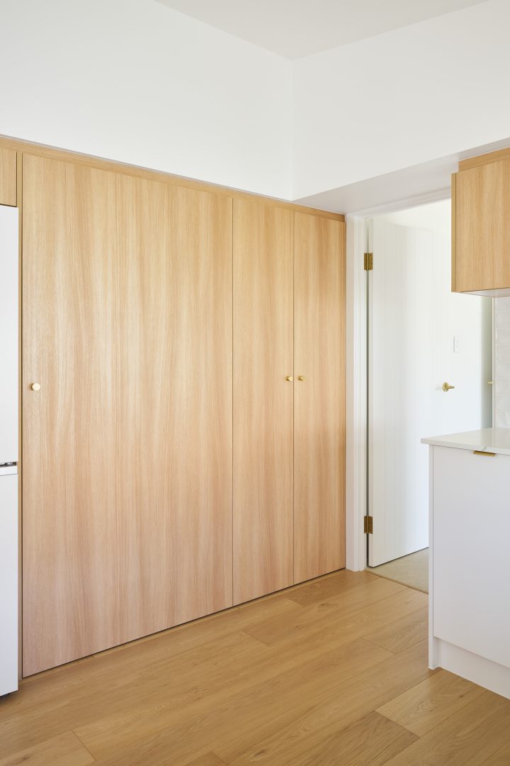 Minimalist kitchen with wooden cabinets and open door.