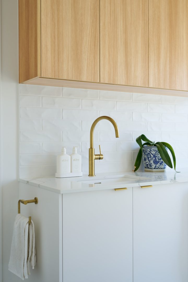 Modern kitchen sink with brass faucet and decor.