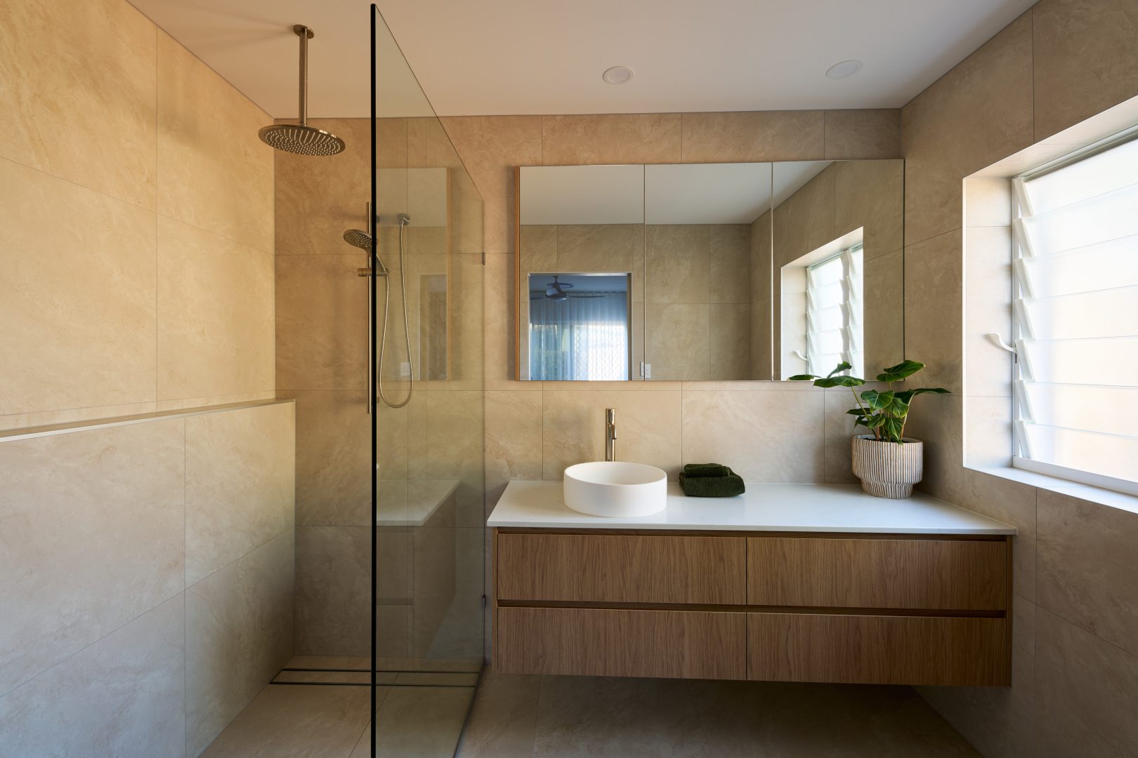 Modern bathroom with glass shower and wooden vanity.