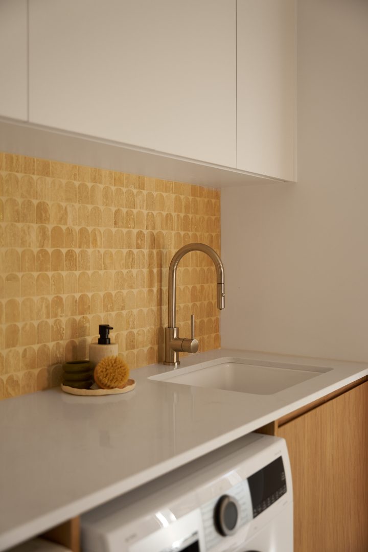 Modern kitchen sink with gold backsplash and faucet.