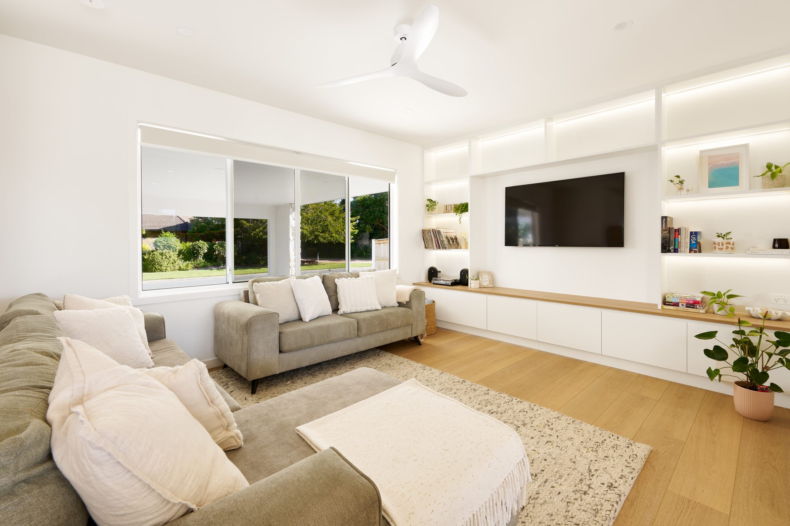 Modern living room with large window, TV, and sofa.