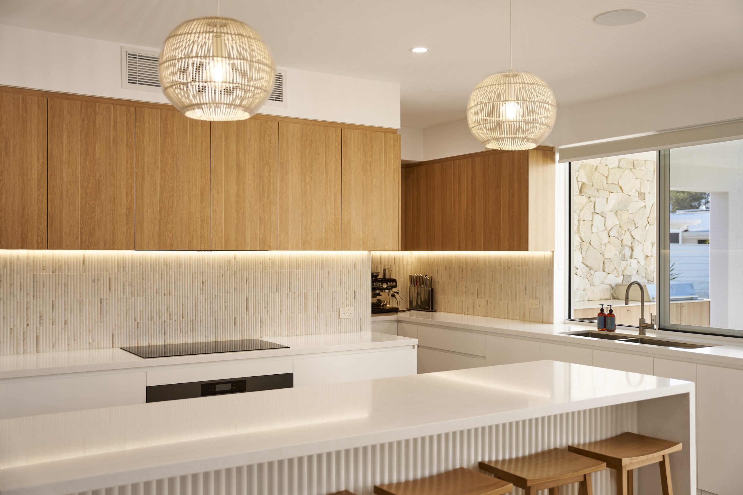 Modern kitchen with island, wooden cabinets, pendant lights.